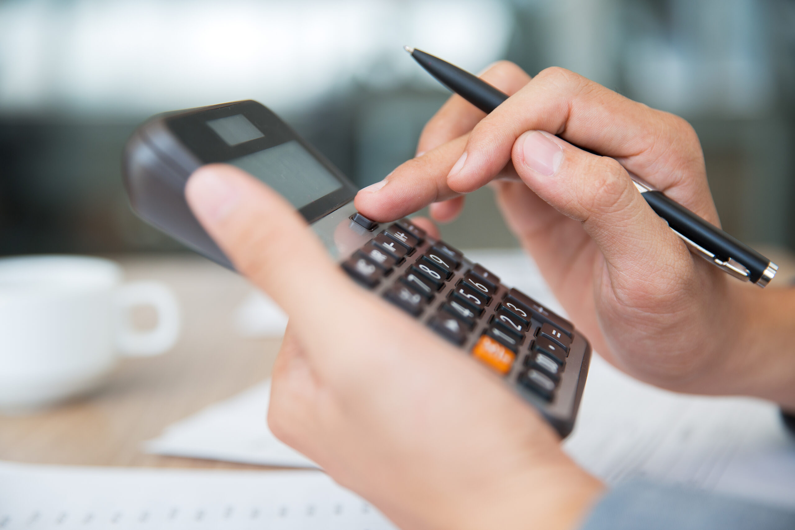 Close-up of male hands using calculator. Unrecognizable accountant holding pen when pushing button on calculator. Finance concept